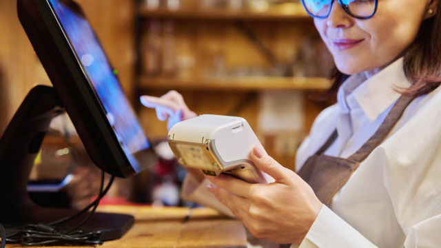 Personal usando TPV y pasarela de pago moderna en un punto de venta.